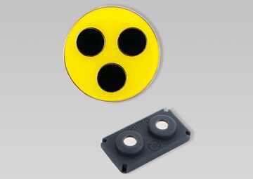 Plakette und eine kleiner schwarzer Magnet.