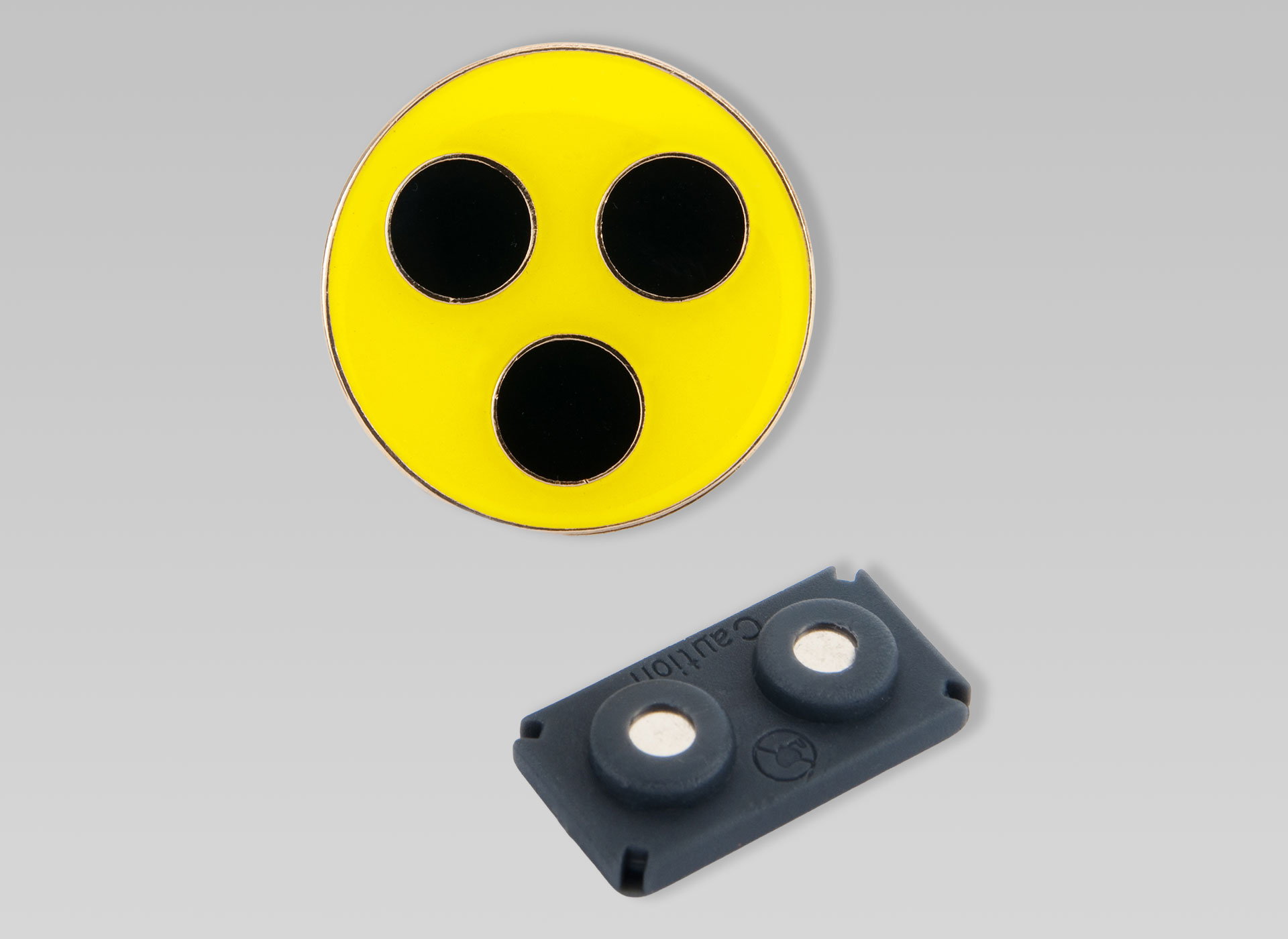 Plakette und eine kleiner schwarzer Magnet.