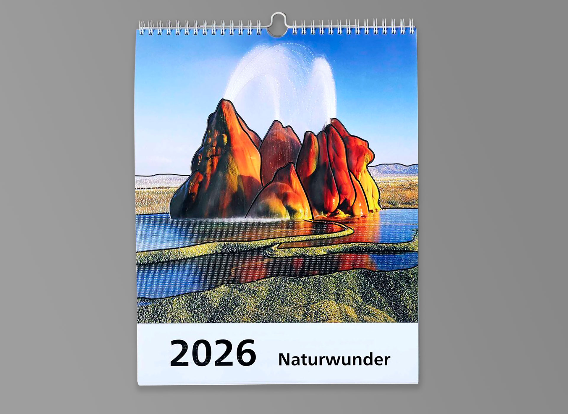 Ansicht auf einen Wandkalender 2026 mit Brailleschrift und Schwarzschrift über Naturwunder